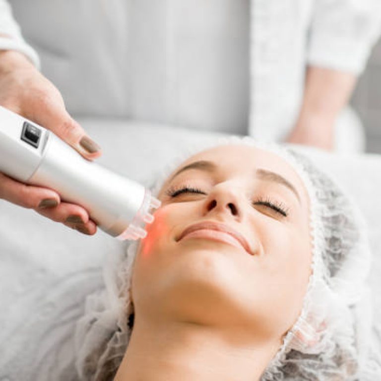 Young woman during a facial massage with professional tool at the medical center